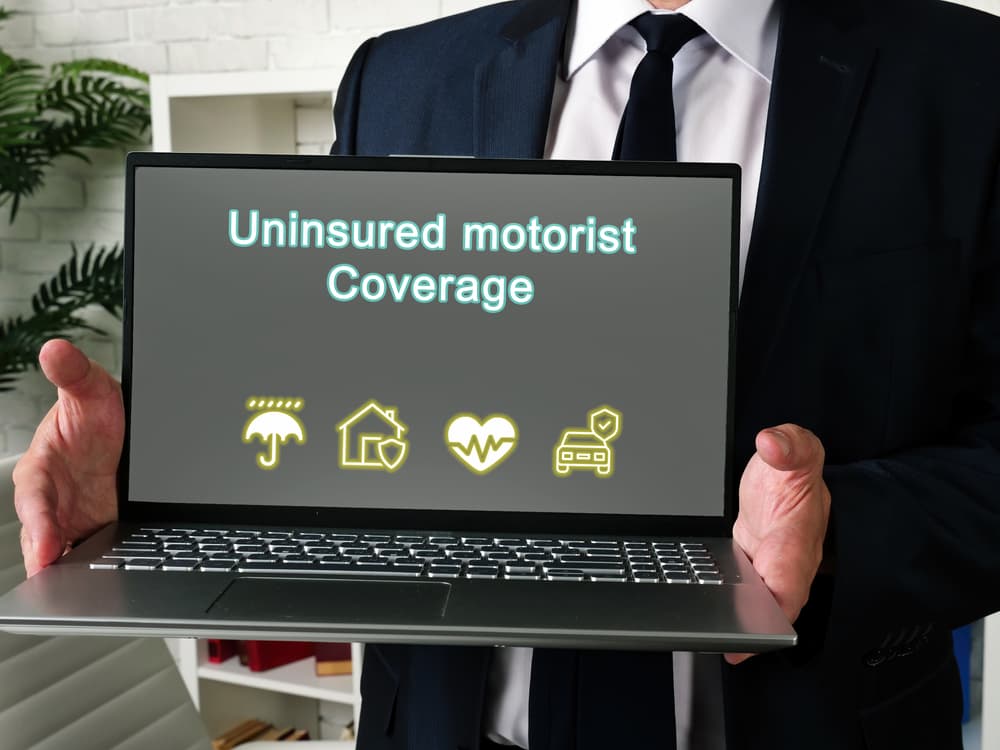 Car accident lawyer showing laptop with ‘Uninsured Motorist Coverage’ text, representing legal help for UM/UIM insurance claims after accidents.