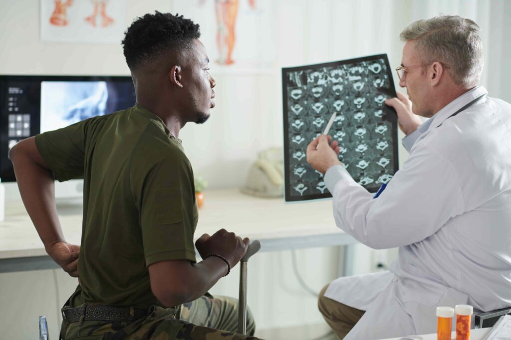 Doctor reviewing spinal MRI scan with male patient experiencing lower back pain during medical consultation in a clinic