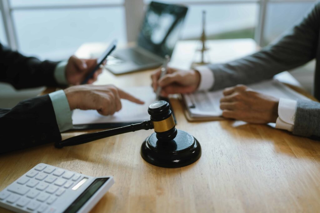 Lawyers discussing a legal case at a desk with a judge&rsquo;s gavel, calculator, and documents, representing legal consultation and case negotiation