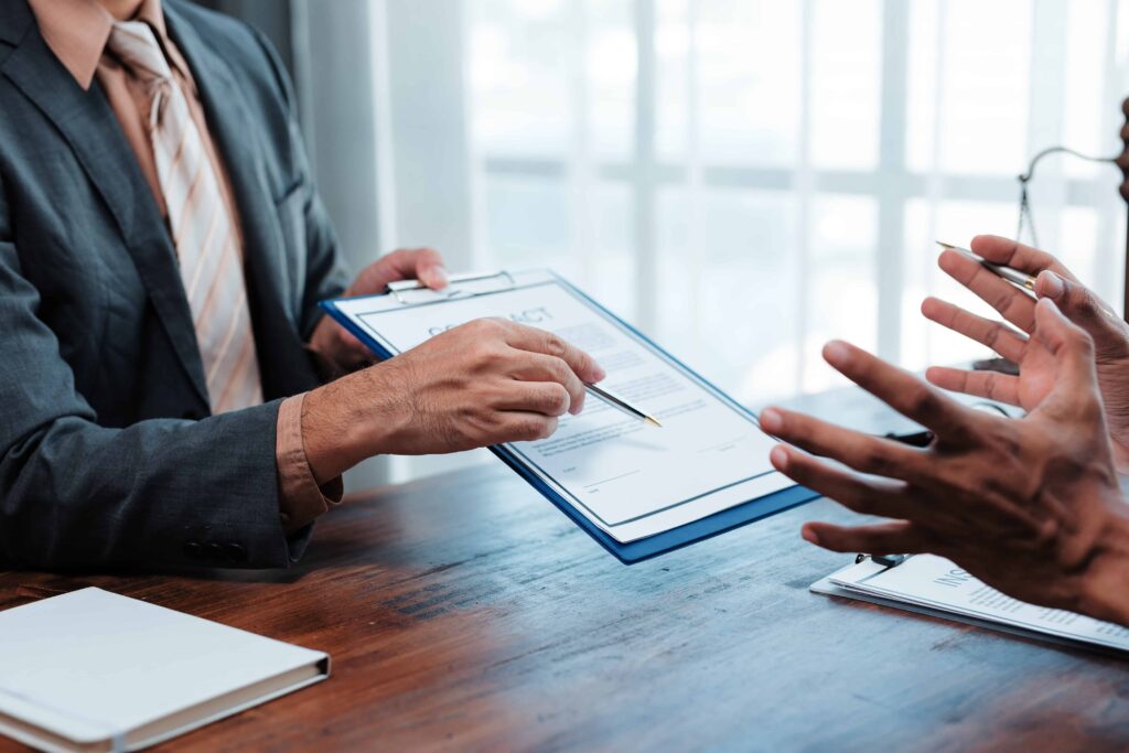 Lawyer explaining legal contract to client during consultation, pointing to document on clipboard in office setting