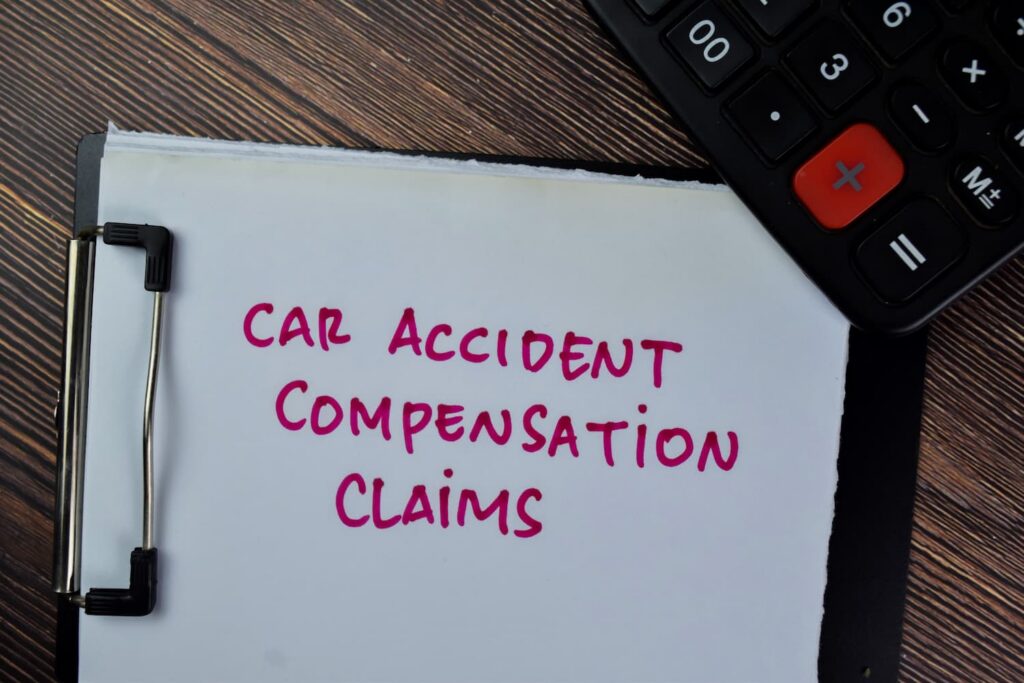 Car accident compensation claims concept showing a clipboard labeled car accident compensation claims with calculator on a desk